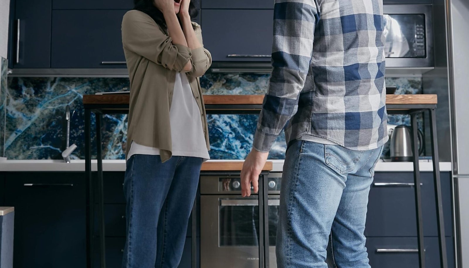 A couple arguing in a modern kitchen, surrounded by flying papers. Emotionally tense moment.